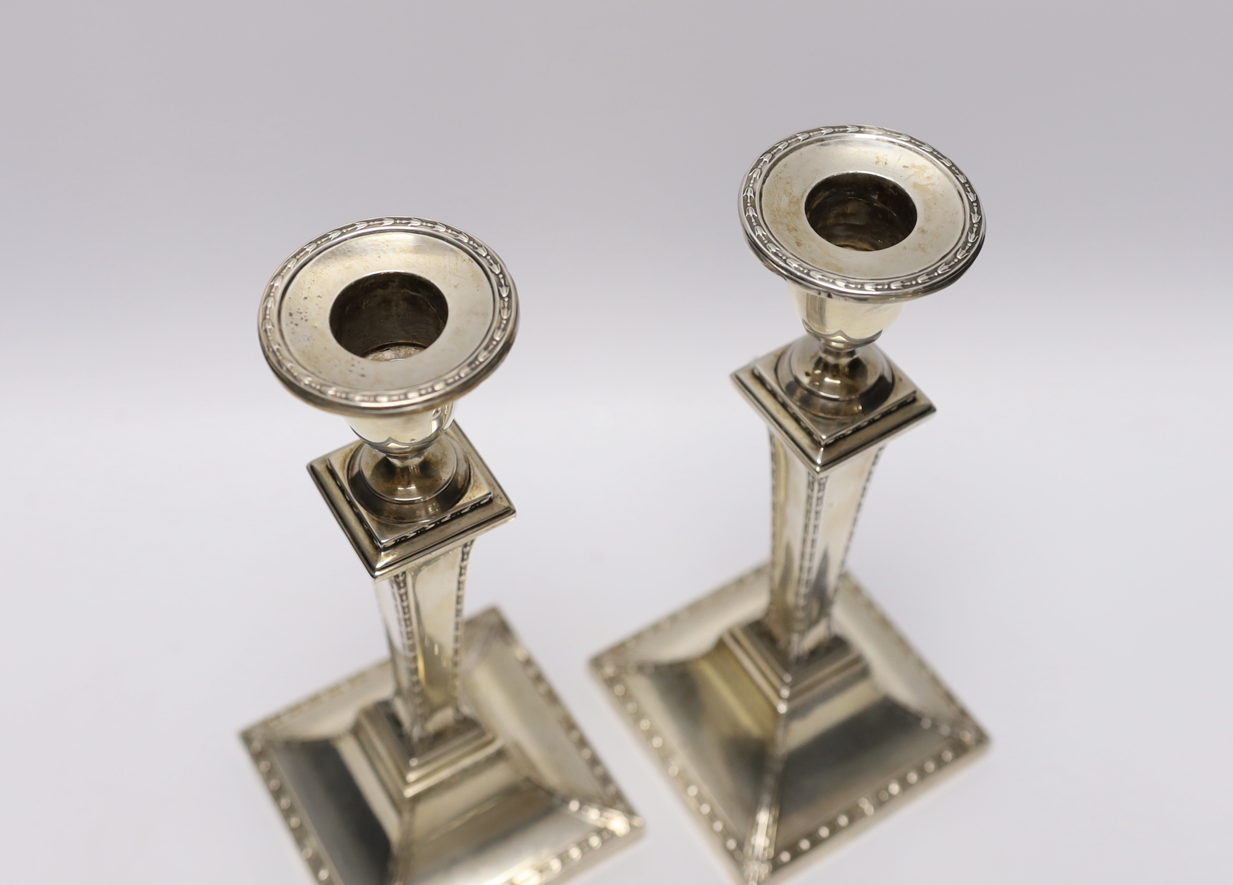 A pair of Edwardian silver candlesticks, with tapering square stems, Stewart Dawson & Co Ltd, London, 1909, height 22.3cm, weighted.